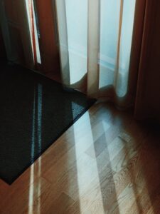 Sunlight streaming through curtains onto wooden floored room, creating a cozy ambiance.